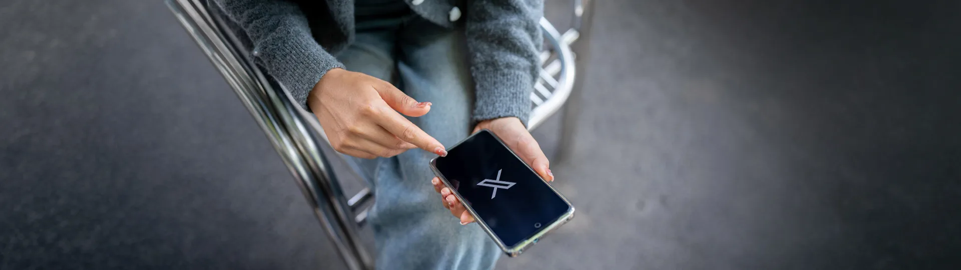 Person tapping a smartphone showing the X logo