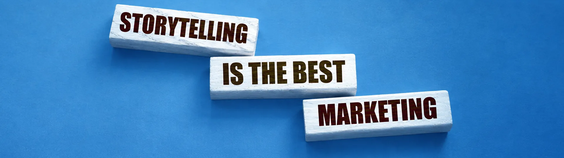 Three wooden blocks on a blue background reading Storytelling is the best marketing