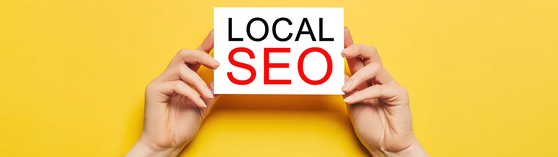 Hands holding a card reading Local SEO against a yellow background