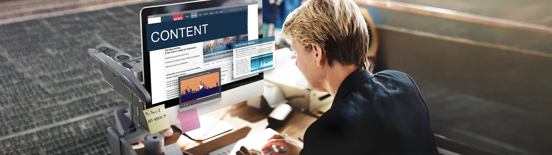 Person at a desk working on a monitor showing web content and article layouts