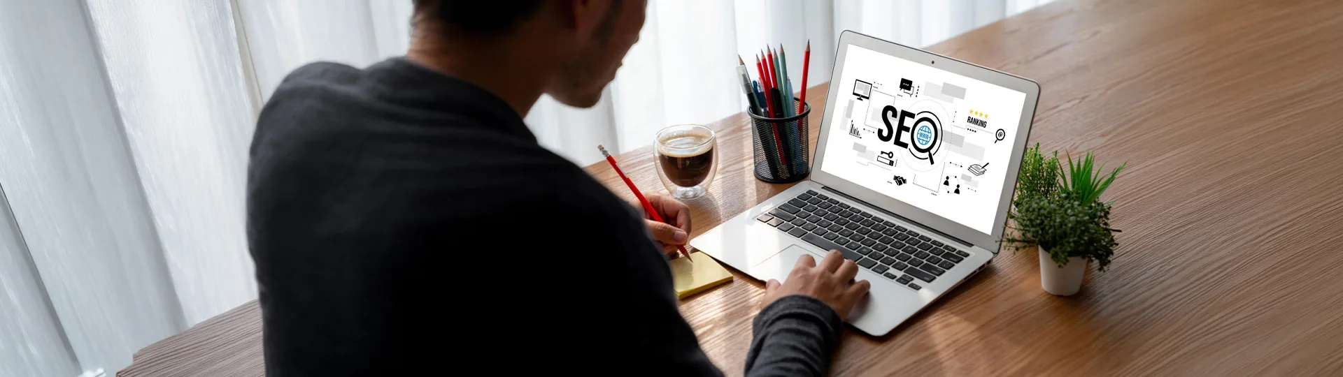 Person working at a laptop showing an SEO ranking dashboard on a wooden desk